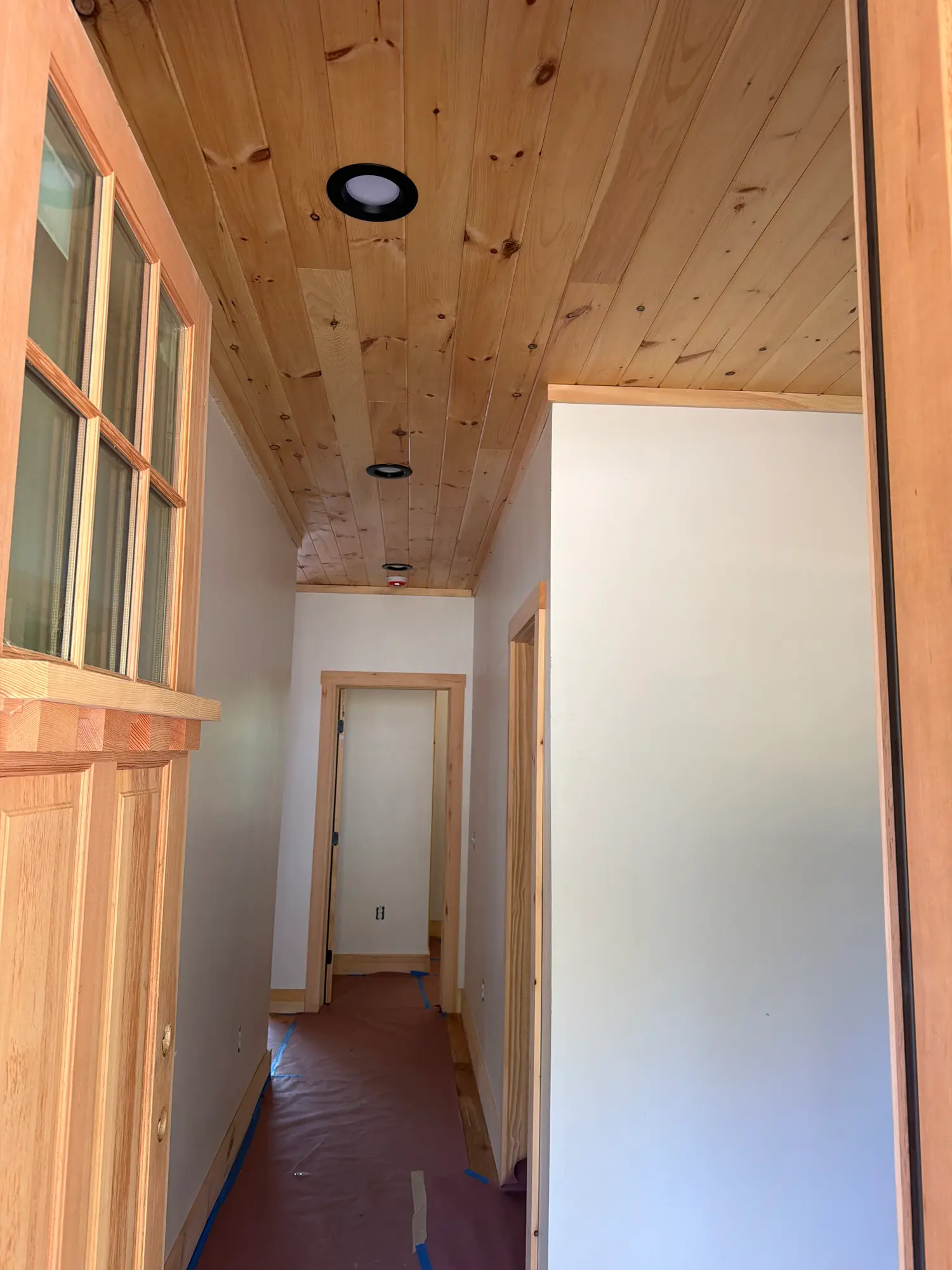 Cabin hallway with a pine tongue-and-groove ceiling and matching wood trim