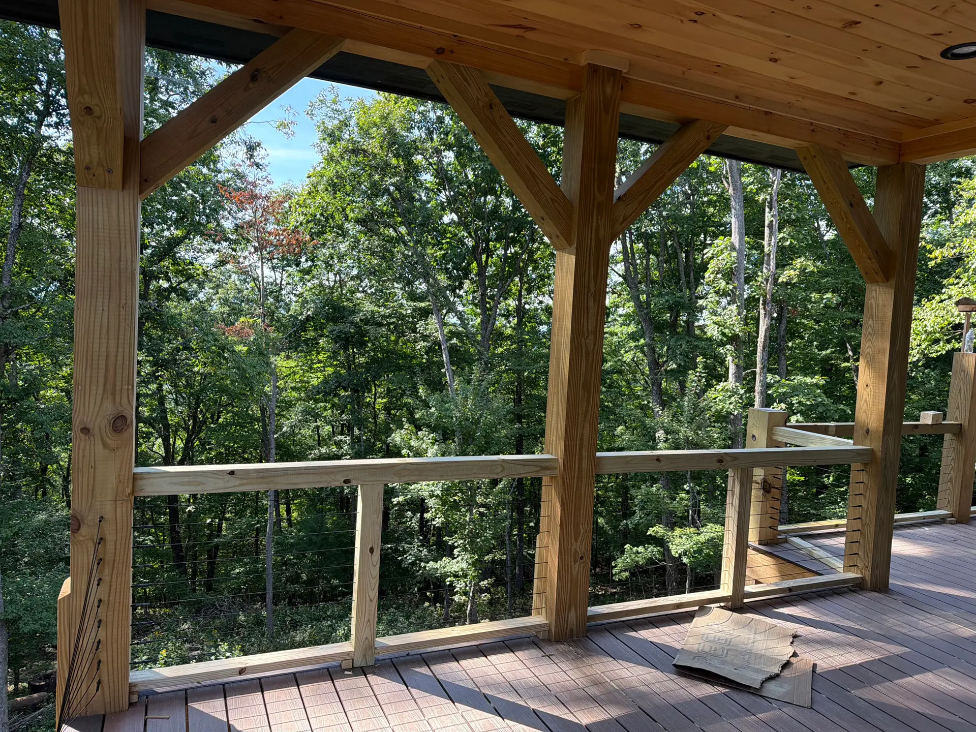 Timber-framed cabin deck with cable rail looking into the woods